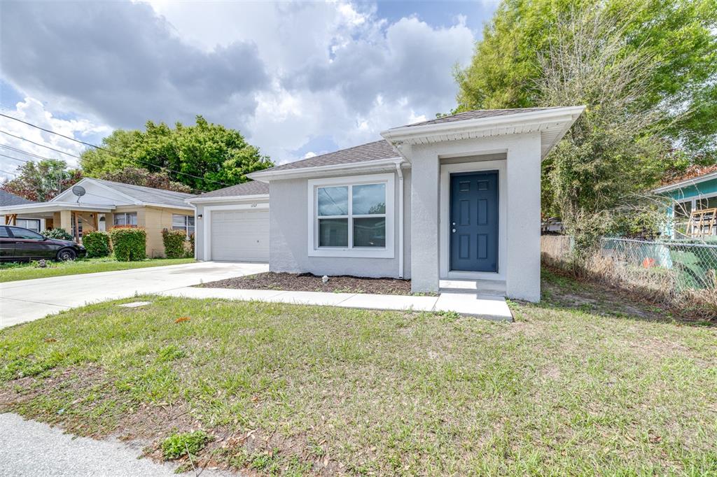 A gray single-story house with a white garage, a dark front door, and a grassy yard — 1727 SECOND STREET NE, WINTER HAVEN, FL
