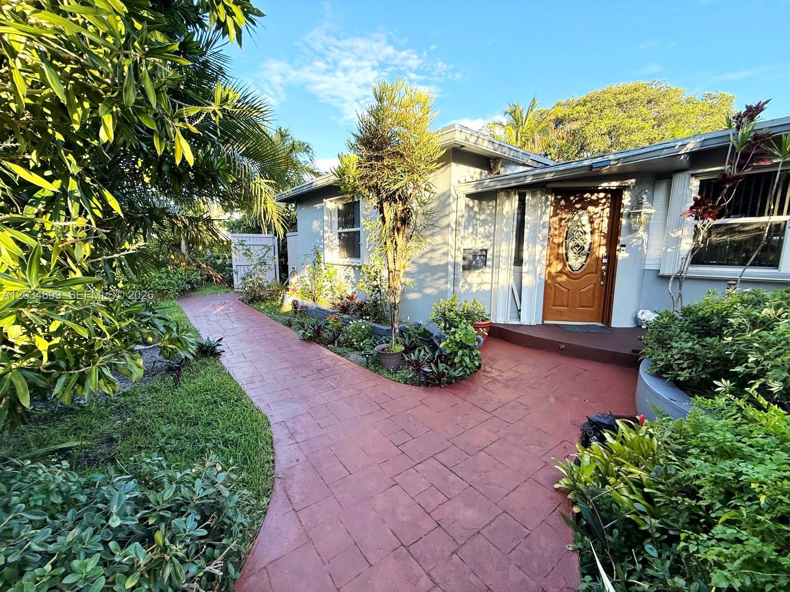 A red paved walkway leads to the front entrance of a gray single-story house — 2630 Monroe St, Hollywood FL 33020, HOLLYWOOD, FL