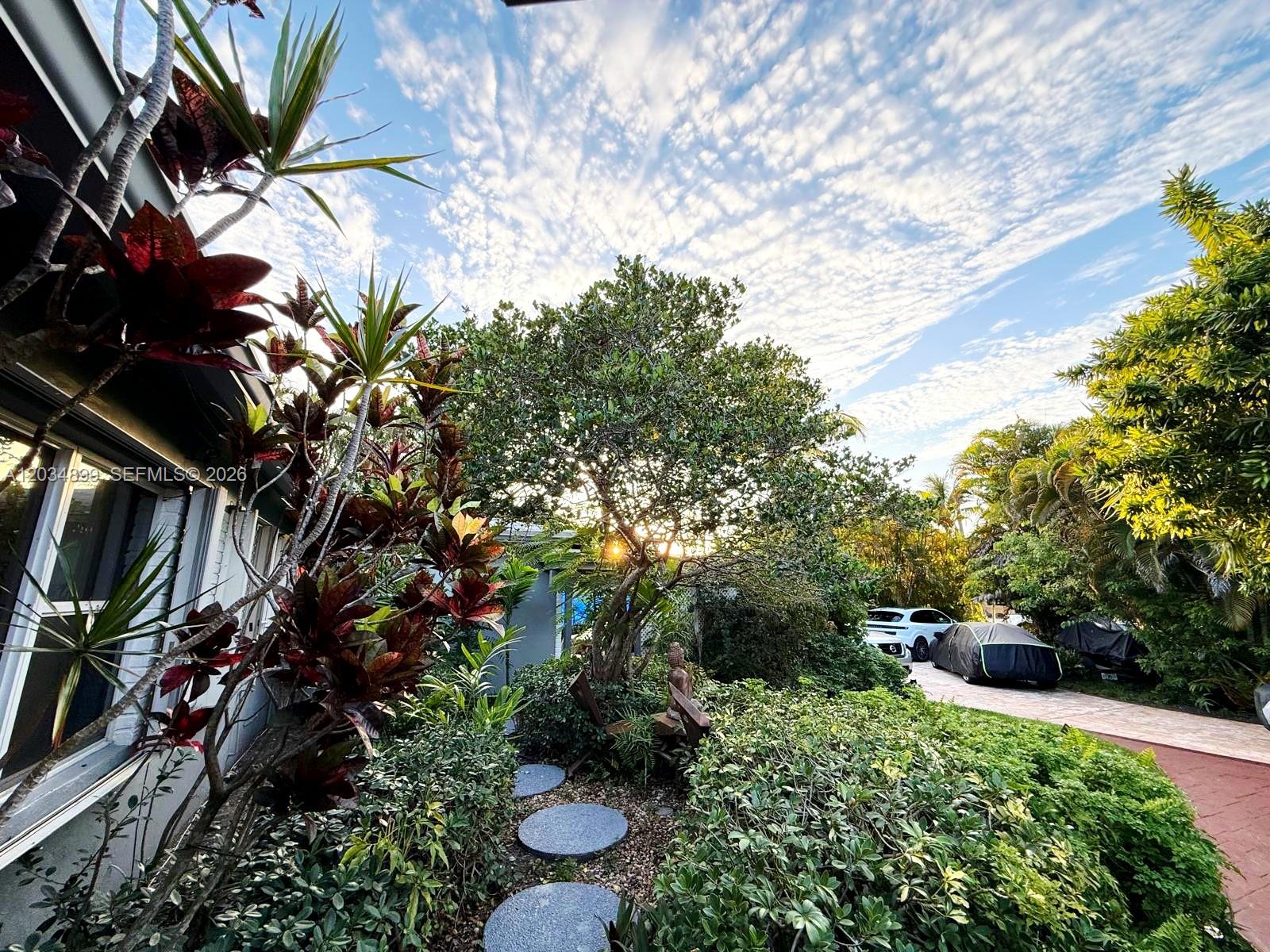 A landscaped front yard features a stone path, lush greenery, and a driveway with cars — 2630 Monroe St, Hollywood FL 33020, HOLLYWOOD, FL