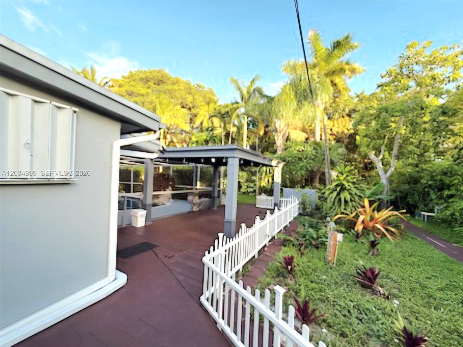 A white picket fence borders a paved patio area next to a house exterior — 2630 Monroe St, Hollywood FL 33020, HOLLYWOOD, FL