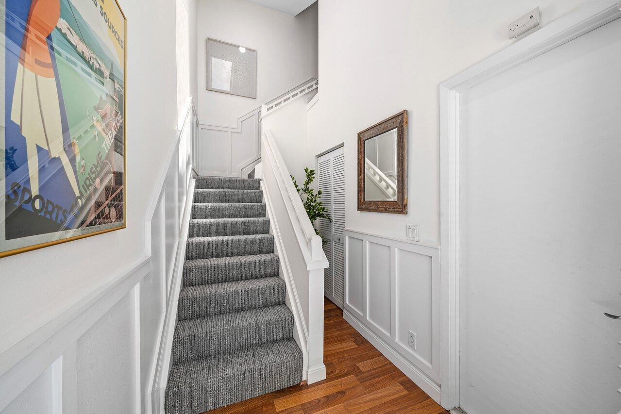 A staircase with gray carpet leads upward in a hallway with white wainscoting and flooring — 5336 Buckhead Circle # 2020, Boca Raton FL 33486, BOCA RATON, FL