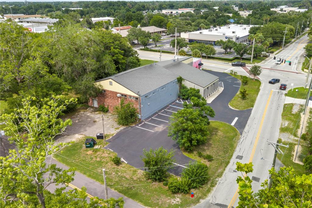 An aerial view shows a commercial building with a pink storefront and a parking lot — 1412 N MAGNOLIA AVENUE, OCALA, FL