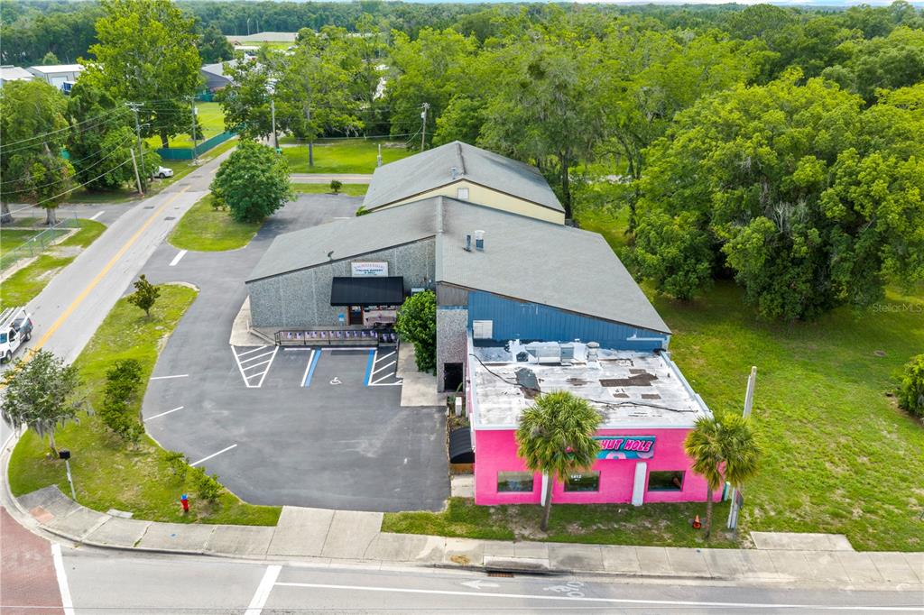 An aerial view shows a commercial building with a parking lot and surrounding trees — 1412 N MAGNOLIA AVENUE, OCALA, FL