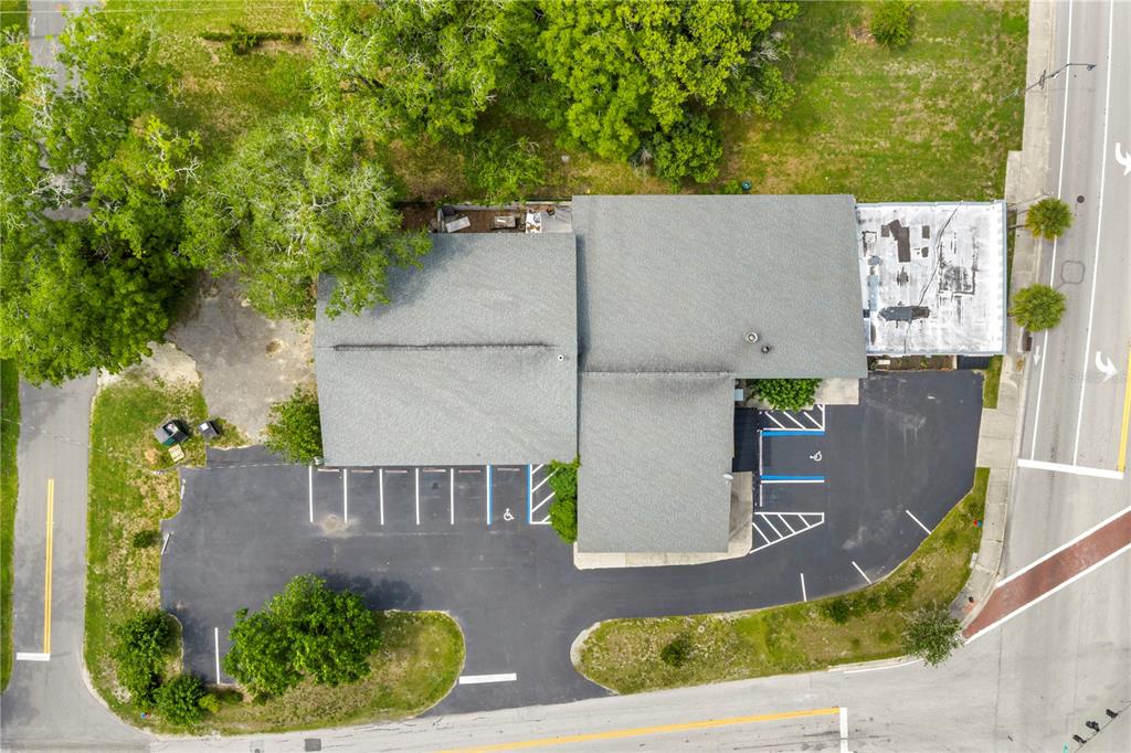 An aerial view shows a commercial building with a parking lot and surrounding trees — 1412 N MAGNOLIA AVENUE, OCALA, FL