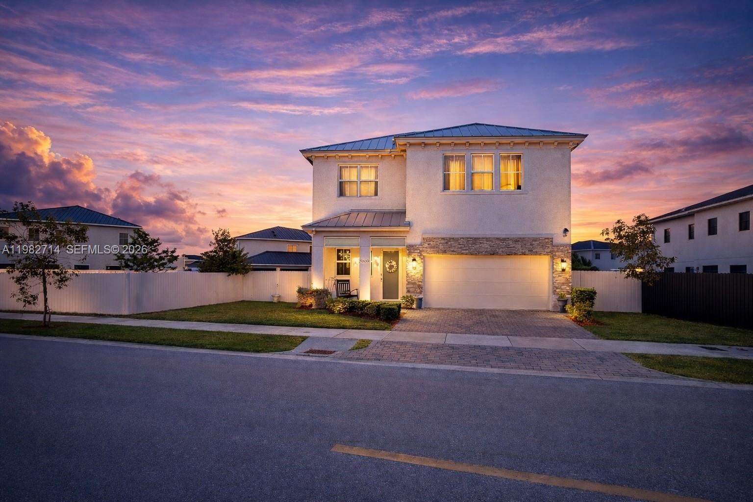 A two-story house with a stone-accented facade and a two-car garage at sunset — 22255 SW 132nd Ave, Miami FL 33170, MIAMI, FL