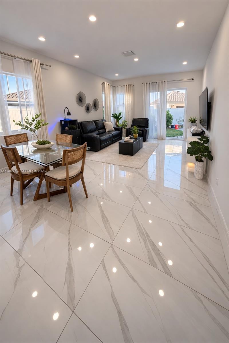 A bright, open-concept living and dining area features white marble-look tile flooring and modern furnishings — 22255 SW 132nd Ave, Miami FL 33170, MIAMI, FL