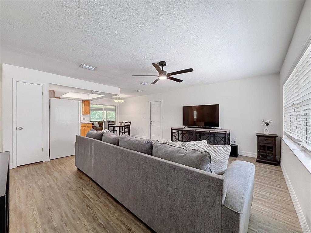 A living room features a gray sectional sofa, a television on a console, and wood-look flooring — 7022 W CRESTVIEW LANE, CRYSTAL RIVER, FL