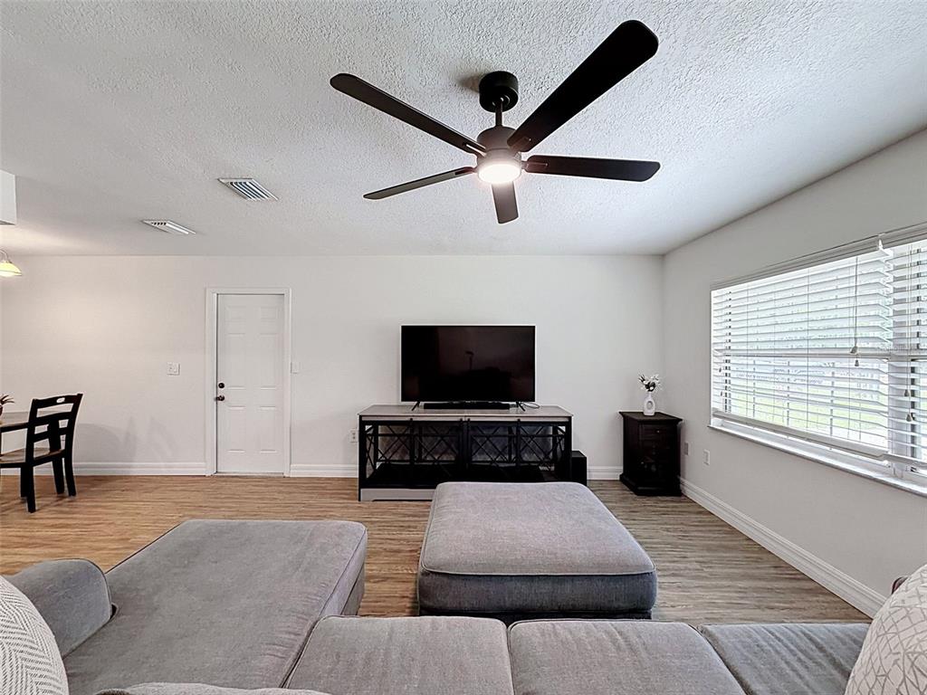 A living room features a gray sectional sofa, a television on a console, and a ceiling fan — 7022 W CRESTVIEW LANE, CRYSTAL RIVER, FL