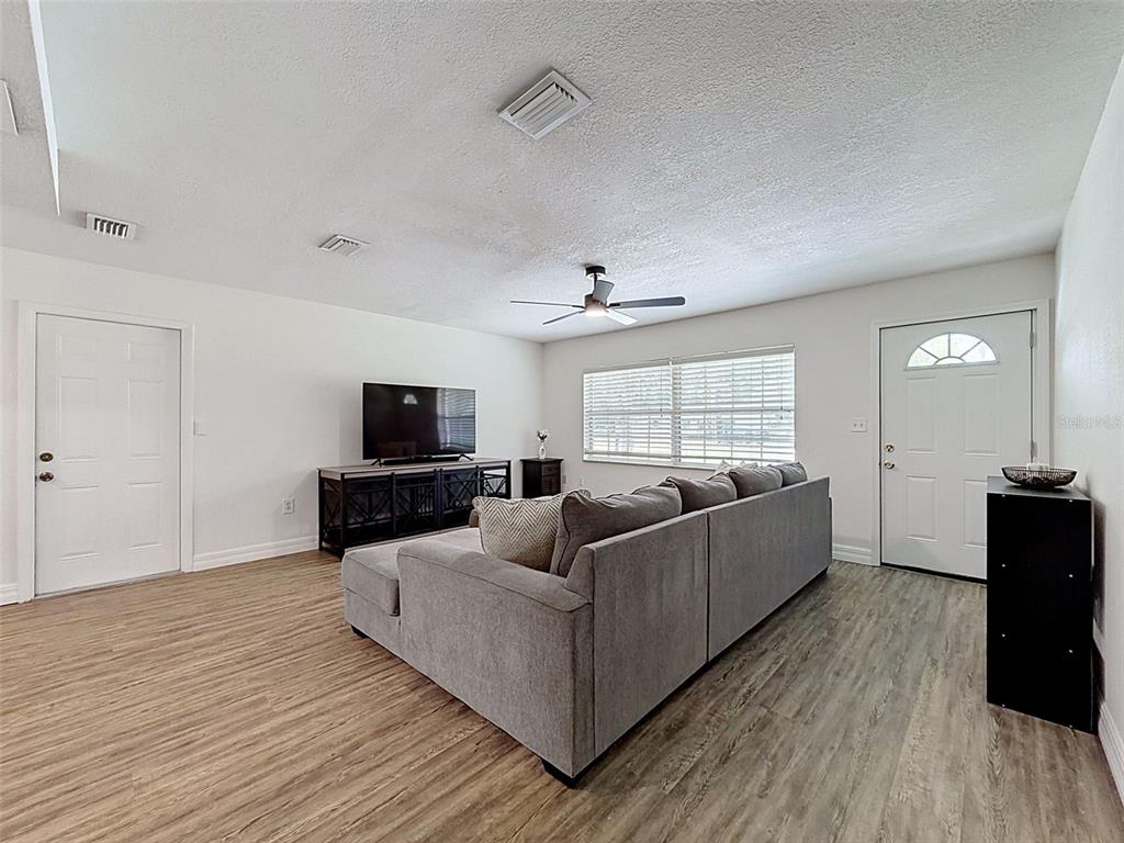 A living room features light wood-look flooring, a gray sectional sofa, and a television console — 7022 W CRESTVIEW LANE, CRYSTAL RIVER, FL