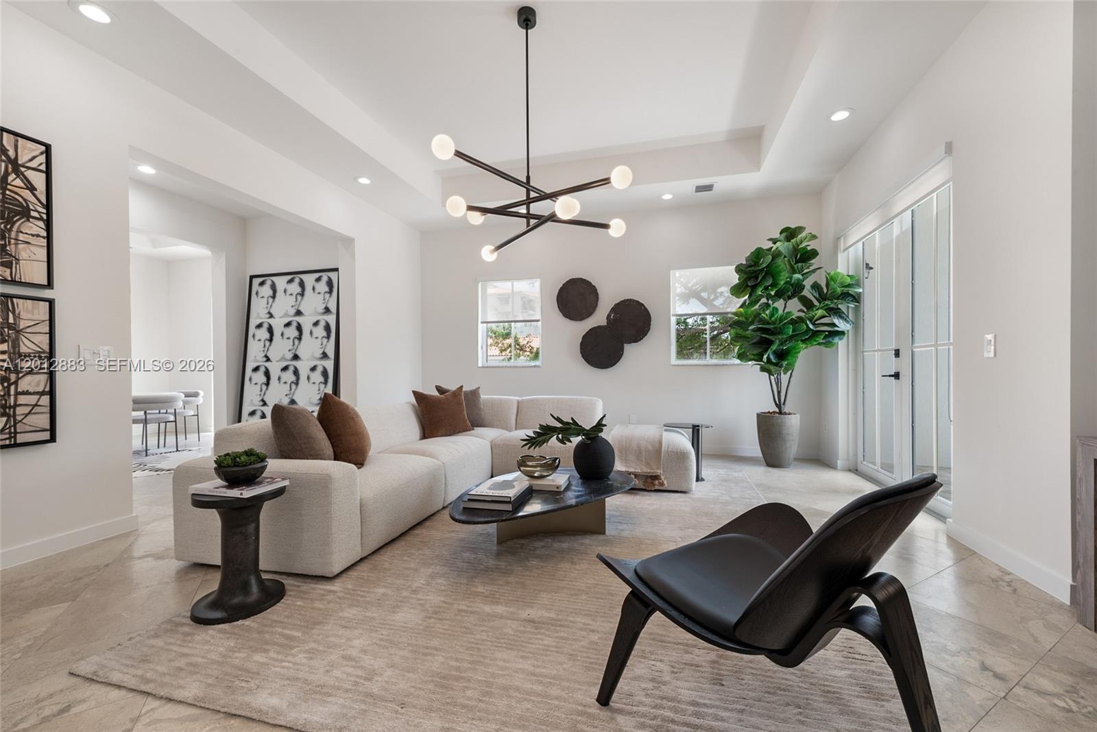 A modern living room features a white sectional sofa, a black chandelier, and tile flooring — 349 Madeira Ave # 349, Coral Gables FL 33134, CORAL GABLES, FL