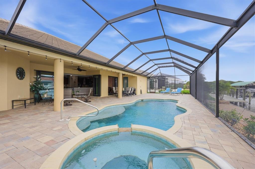A screened-in patio features a swimming pool, a hot tub, and tile flooring — 15260 LEIPZIG CIRCLE, PORT CHARLOTTE, FL
