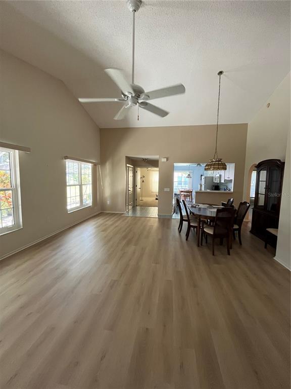 A spacious living and dining area features vaulted ceilings, light wood flooring, and a ceiling fan — 2387 BENTLEY DRIVE, PALM HARBOR, FL