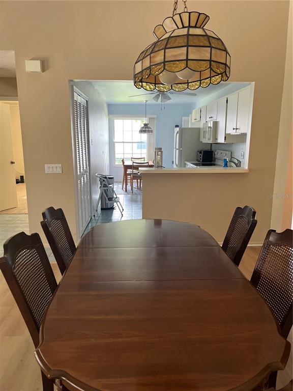 A dining room with a wooden table and chairs overlooks a kitchen and breakfast nook — 2387 BENTLEY DRIVE, PALM HARBOR, FL