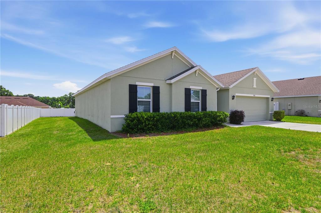 A light green single-story house with black shutters and a two-car garage — 3902 SE 99TH STREET, BELLEVIEW, FL