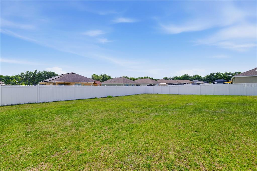 A large, grassy backyard is enclosed by a white vinyl privacy fence — 3902 SE 99TH STREET, BELLEVIEW, FL