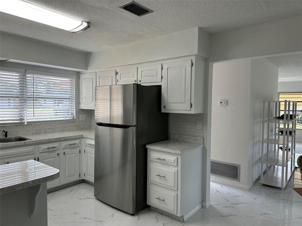 A kitchen features white cabinets, stainless steel appliances, marble-look tile flooring, and a window — 470 LAKE ROAD, OCALA, FL