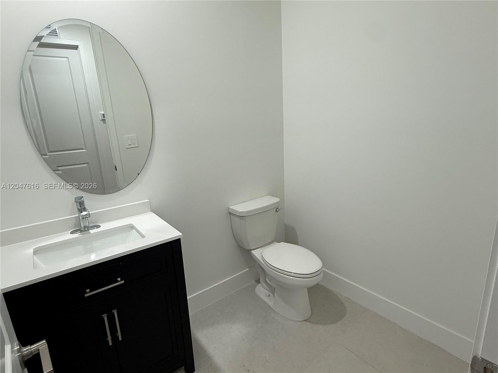 A bathroom features a black vanity with a white countertop, oval mirror, and white toilet — 4255 SW 123rd Ter, Davie FL 33330, DAVIE, FL