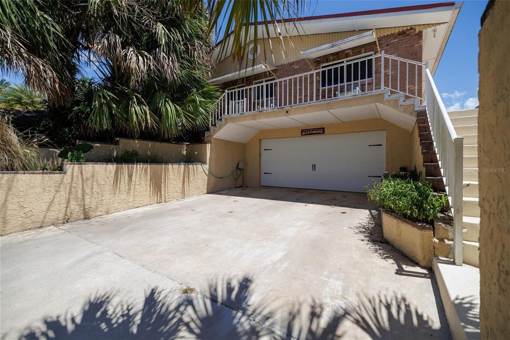 A two-story house with a white garage door, a concrete driveway, and an exterior staircase — 1413 N ATLANTIC AVENUE, NEW SMYRNA BEACH, FL