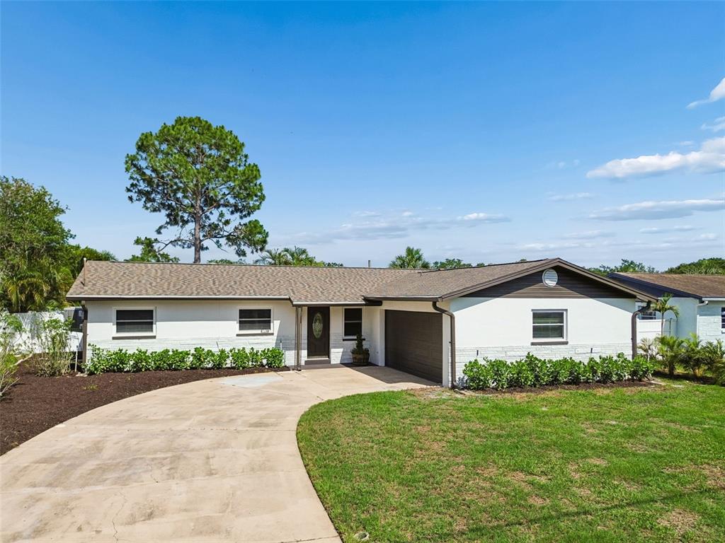 A single-story white brick house with a brown roof, a garage, and a curved driveway — 6003 TAMPA SHORES BOULEVARD, TAMPA, FL