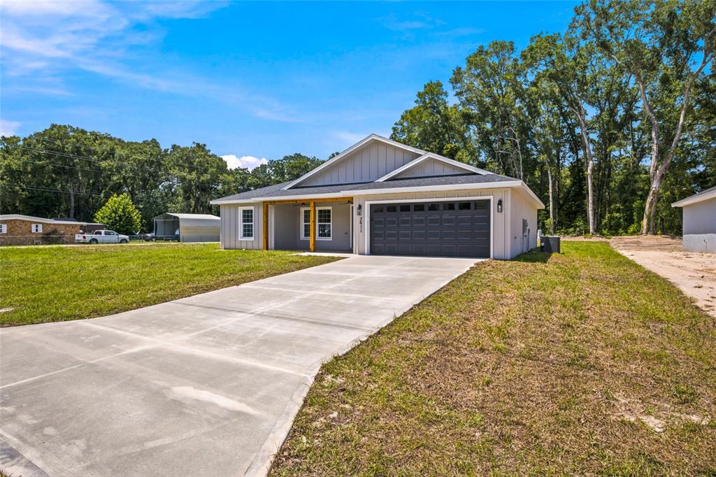 A single-story house with gray siding, a dark garage door, and a concrete driveway — 3611 SE 140TH PLACE, SUMMERFIELD, FL