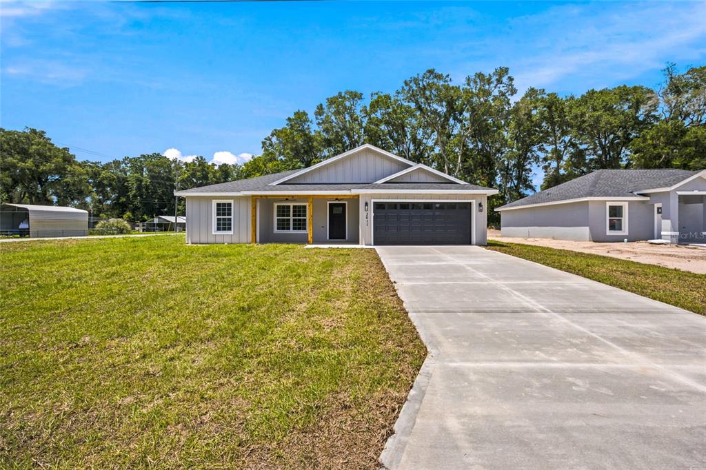 A single-story house with gray siding, a dark garage door, and a concrete driveway — 3611 SE 140TH PLACE, SUMMERFIELD, FL
