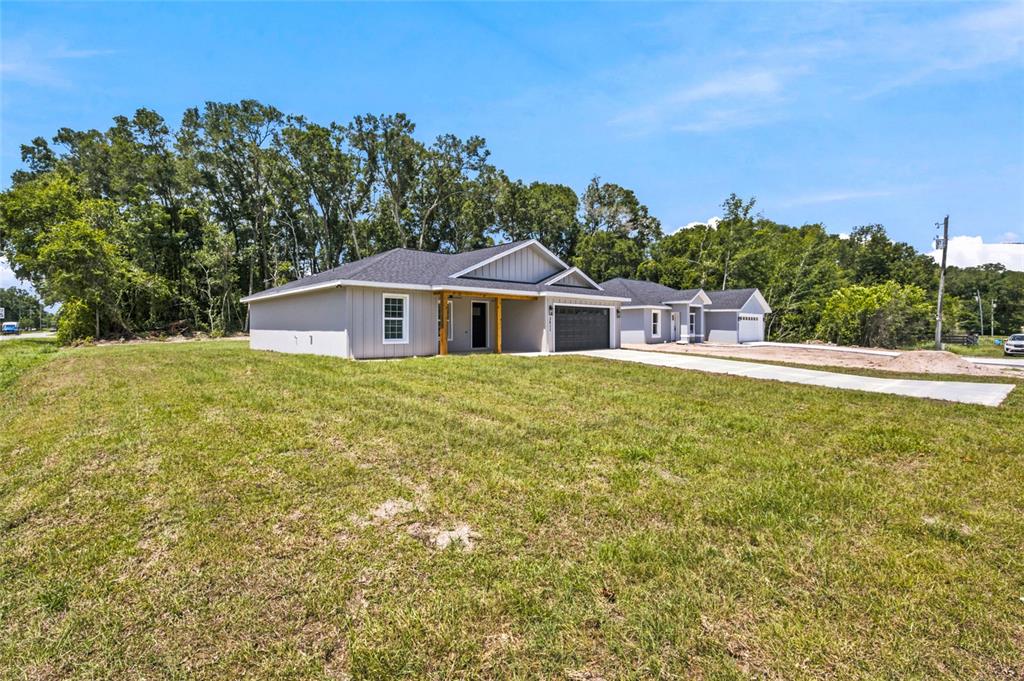 A single-story house with a gray exterior, dark roof, and concrete driveway sits on grass — 3611 SE 140TH PLACE, SUMMERFIELD, FL