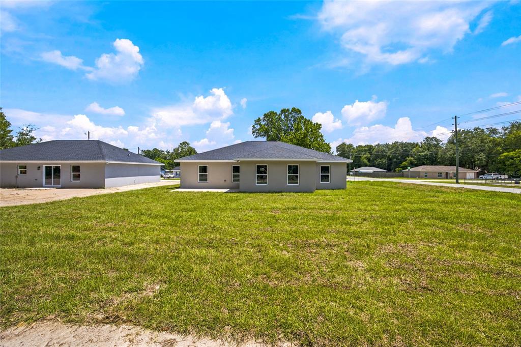 The exterior of a newly constructed single-story house with a large grassy yard — 3611 SE 140TH PLACE, SUMMERFIELD, FL