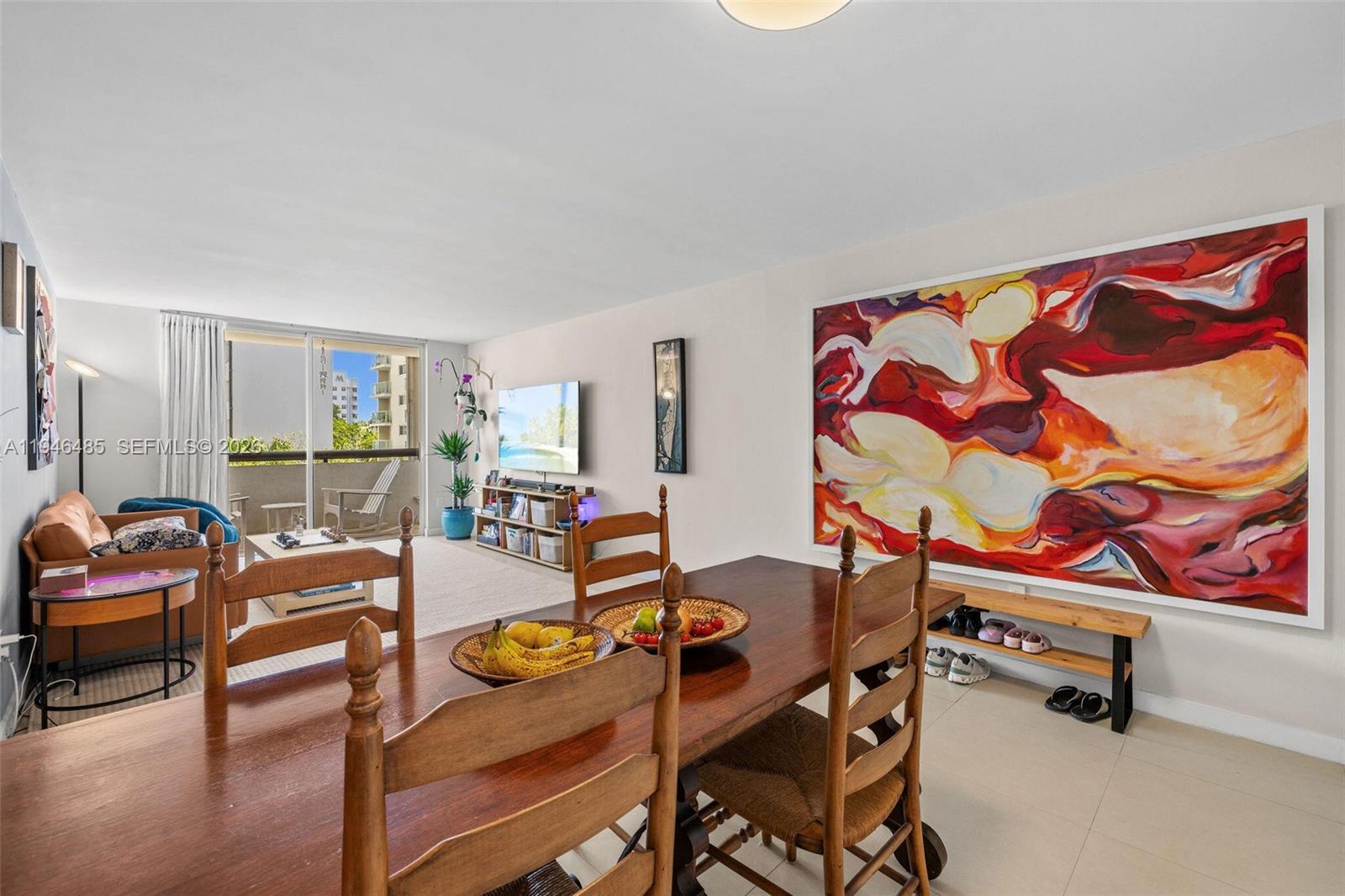 A dining area with a wooden table leads into a living room with a balcony — 1775 Washington Ave # 4C, Miami Beach FL 33139, MIAMI BEACH, FL