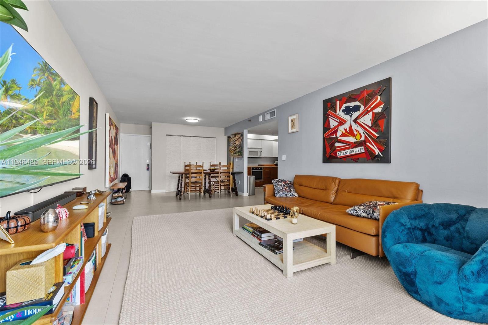 A living room features a tan leather sofa, a blue armchair, and a dining area — 1775 Washington Ave # 4C, Miami Beach FL 33139, MIAMI BEACH, FL