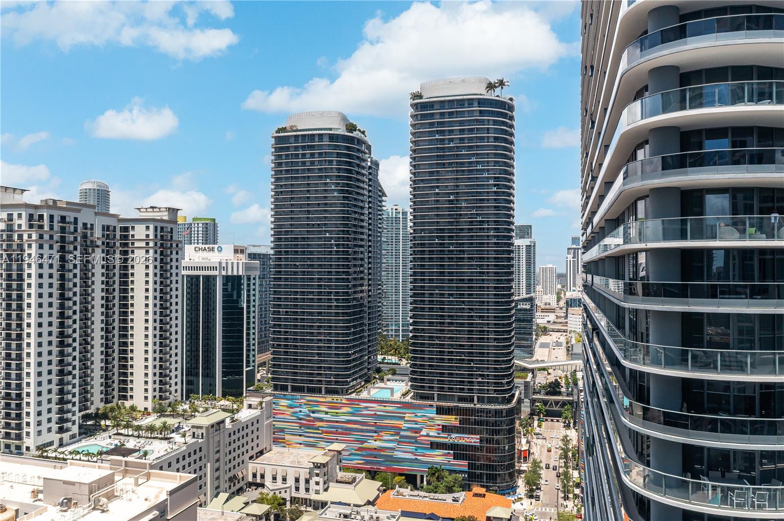 An elevated exterior view of two tall, modern residential towers with a colorful parking garage base — 45 SW 9th St # 1205, Miami FL 33130, MIAMI, FL