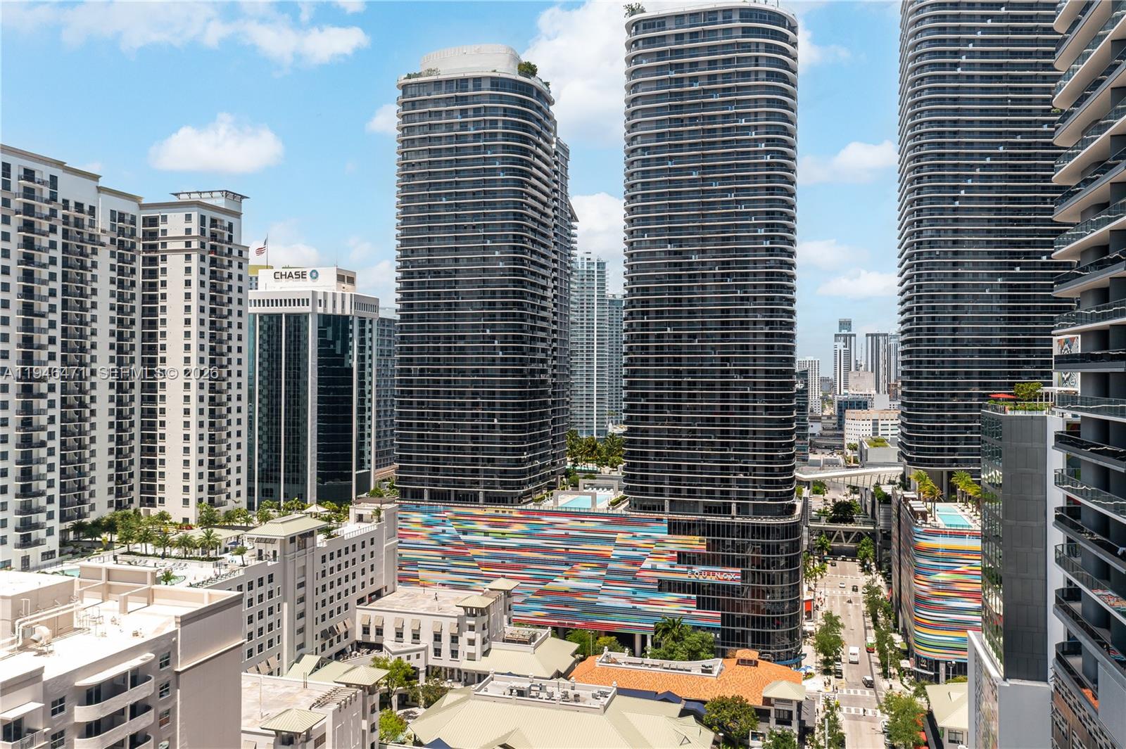 An elevated view of modern high-rise apartment towers featuring colorful geometric facades in a city — 45 SW 9th St # 1205, Miami FL 33130, MIAMI, FL
