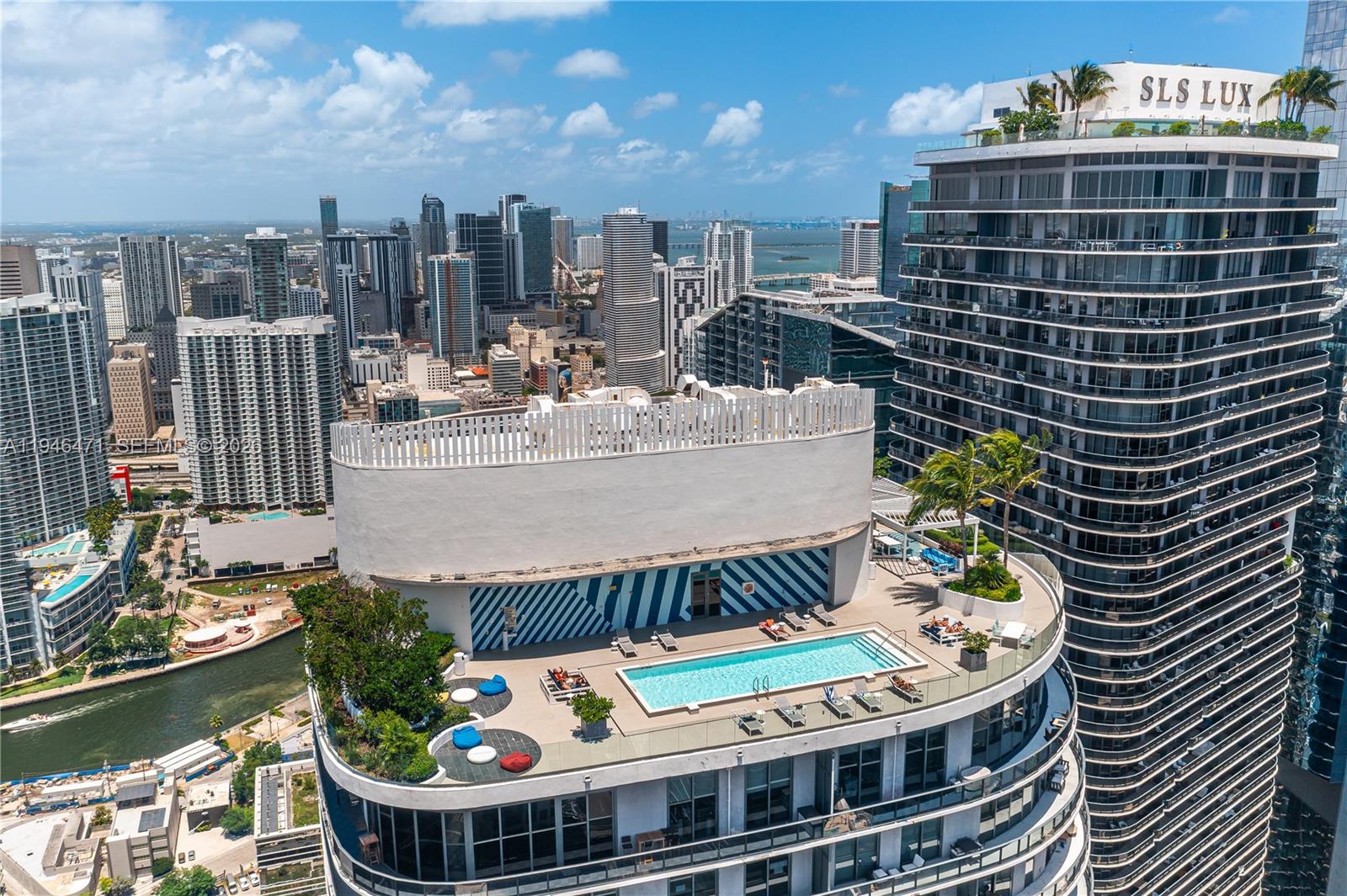 An aerial view of a rooftop pool deck with lounge chairs and city skyline views — 45 SW 9th St # 1205, Miami FL 33130, MIAMI, FL