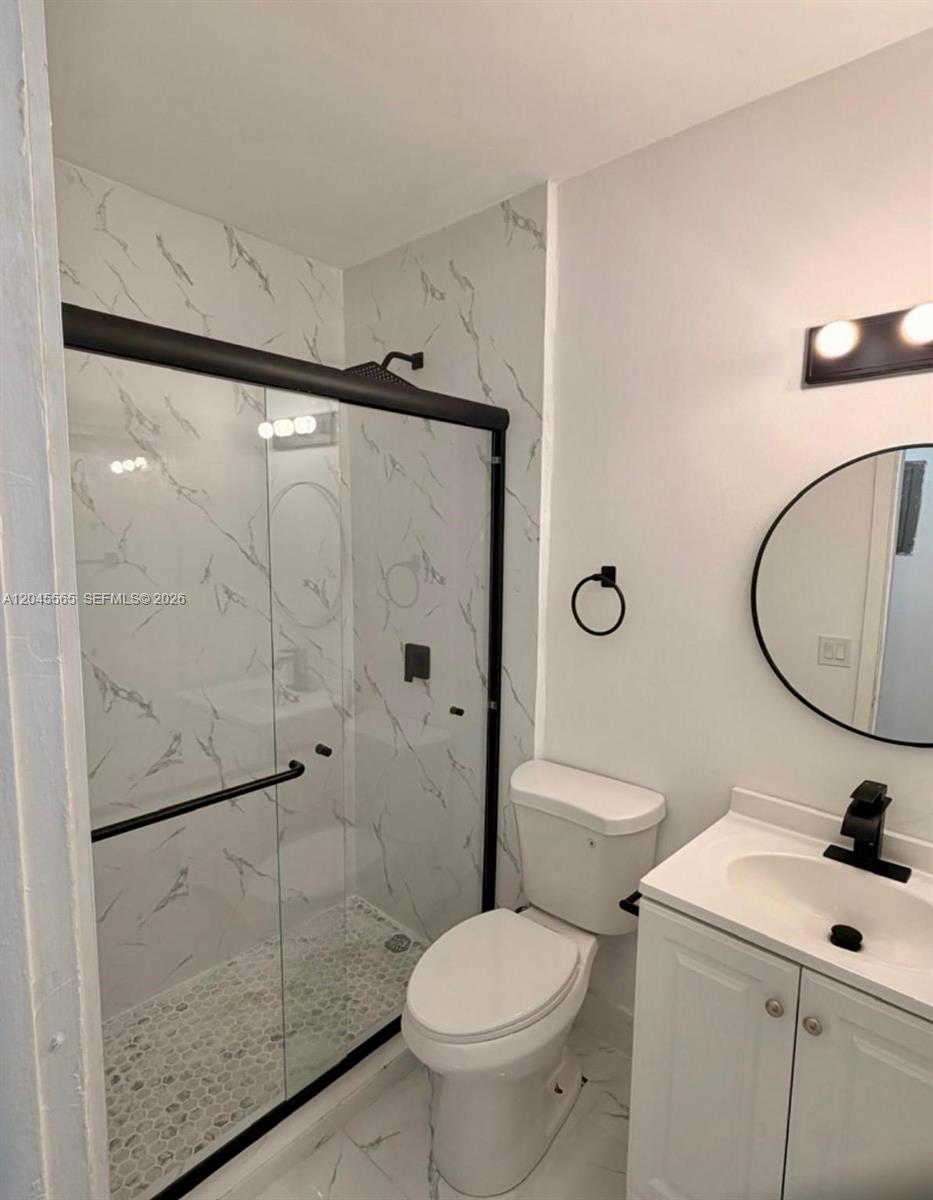 A modern bathroom features a glass-enclosed shower with marble-patterned tile and a white vanity — 7535 NE 2nd Ct # 4, Miami FL 33138, MIAMI, FL
