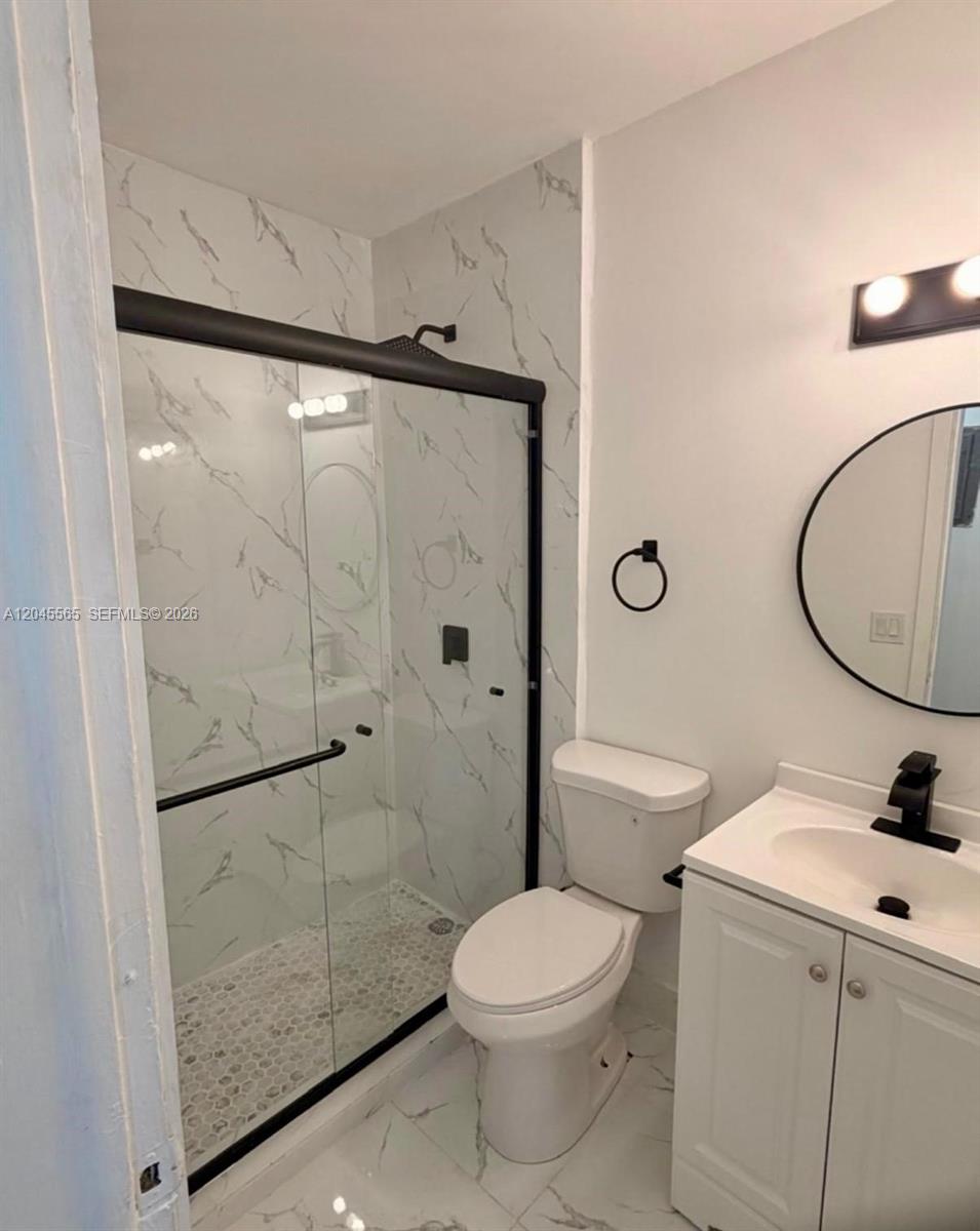 A bathroom features a glass-enclosed shower with marble-patterned tile, a toilet, and a vanity — 7535 NE 2nd Ct # 4, Miami FL 33138, MIAMI, FL