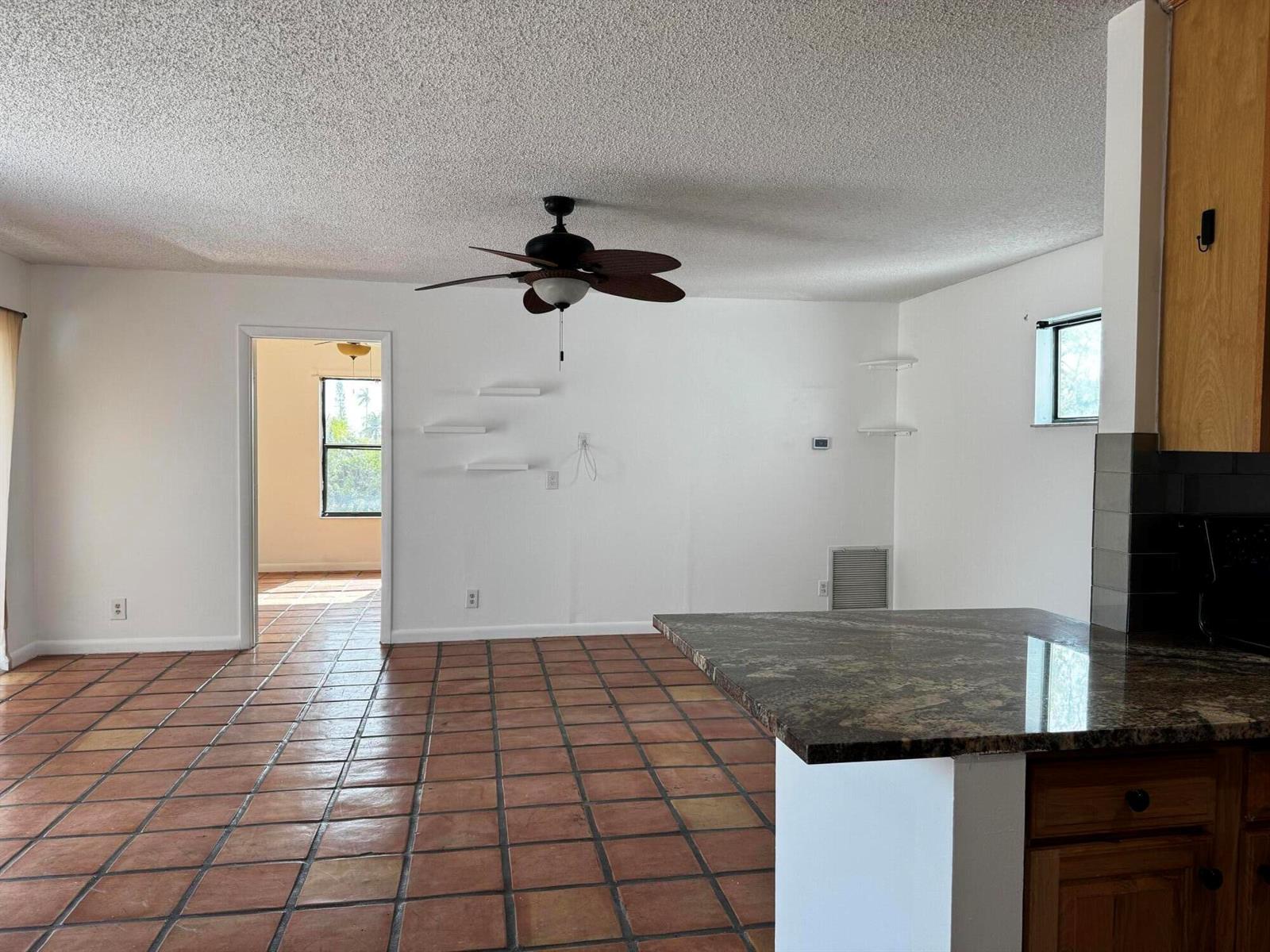 A living room with terracotta tile flooring, a ceiling fan, and white walls — 24 Crossings Circle # H, Boynton Beach FL 33435, BOYNTON BEACH, FL