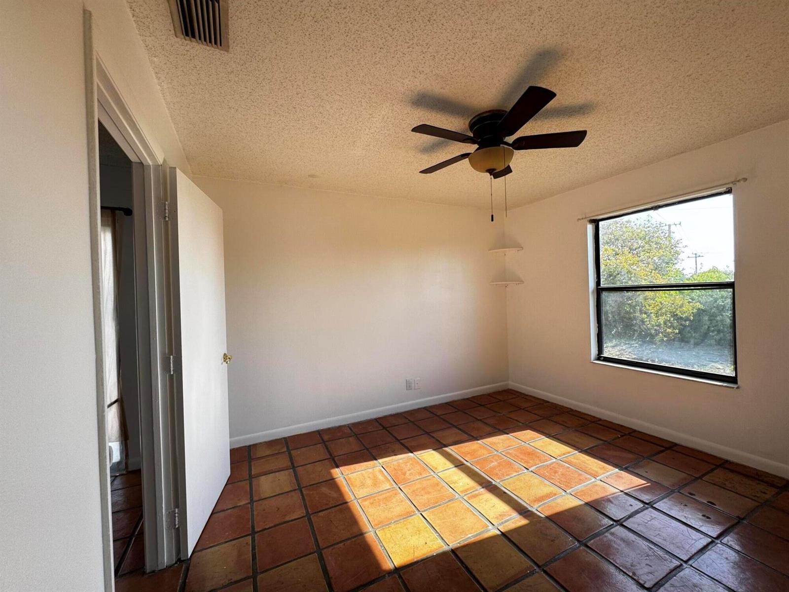 An empty bedroom features terracotta tile flooring, a ceiling fan, and a window — 24 Crossings Circle # H, Boynton Beach FL 33435, BOYNTON BEACH, FL