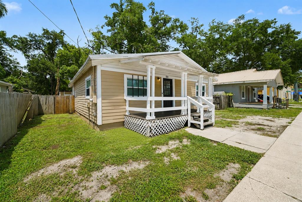 A tan, single-story house with a front porch and white trim sits on a grassy lot — 920 E DR MARTIN LUTHER KING JR BOULEVARD, TAMPA, FL