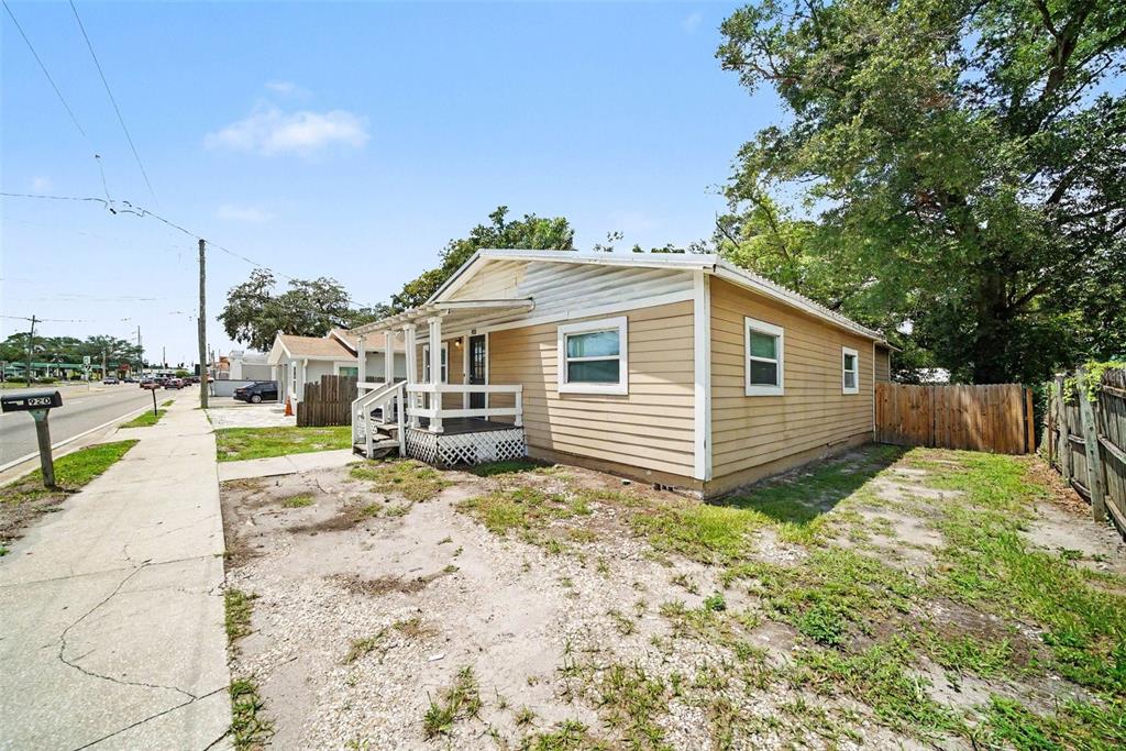 A single-story house with tan siding and a small front porch sits near a sidewalk — 920 E DR MARTIN LUTHER KING JR BOULEVARD, TAMPA, FL