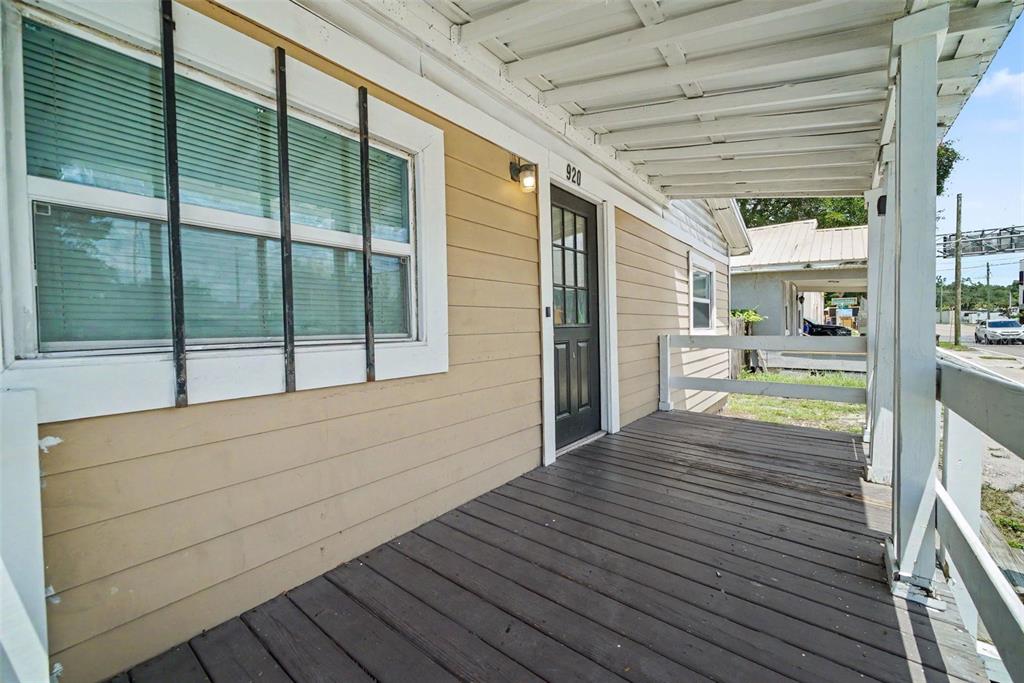 A covered wooden porch with a dark door and a large window on a house — 920 E DR MARTIN LUTHER KING JR BOULEVARD, TAMPA, FL