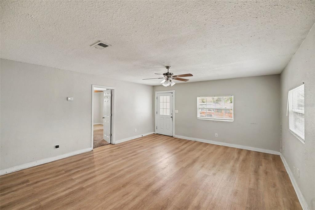 A living room with light gray walls, wood-look flooring, a ceiling fan, and a white door — 920 E DR MARTIN LUTHER KING JR BOULEVARD, TAMPA, FL