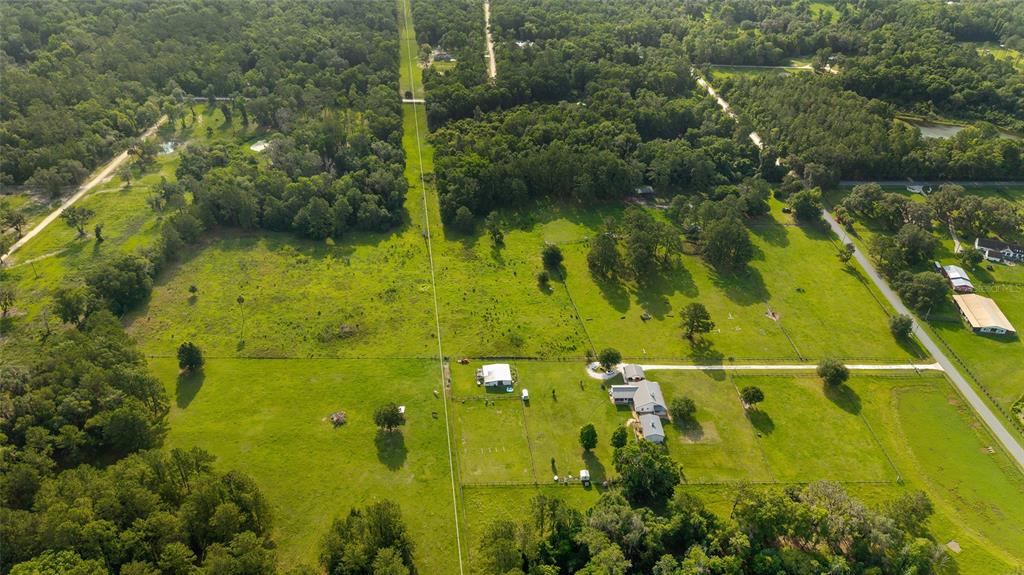 An aerial view shows a rural property with a house, outbuildings, and fenced pastures — 15015 NW 185TH STREET, WILLISTON, FL