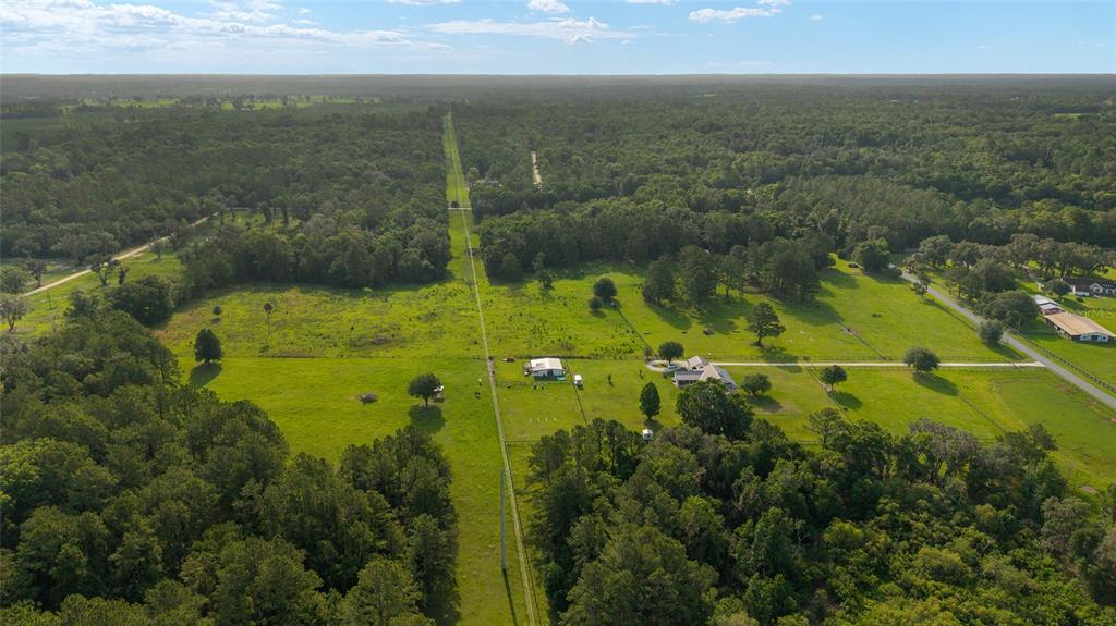 An aerial view shows a rural property with a house, outbuildings, and surrounding wooded land — 15015 NW 185TH STREET, WILLISTON, FL