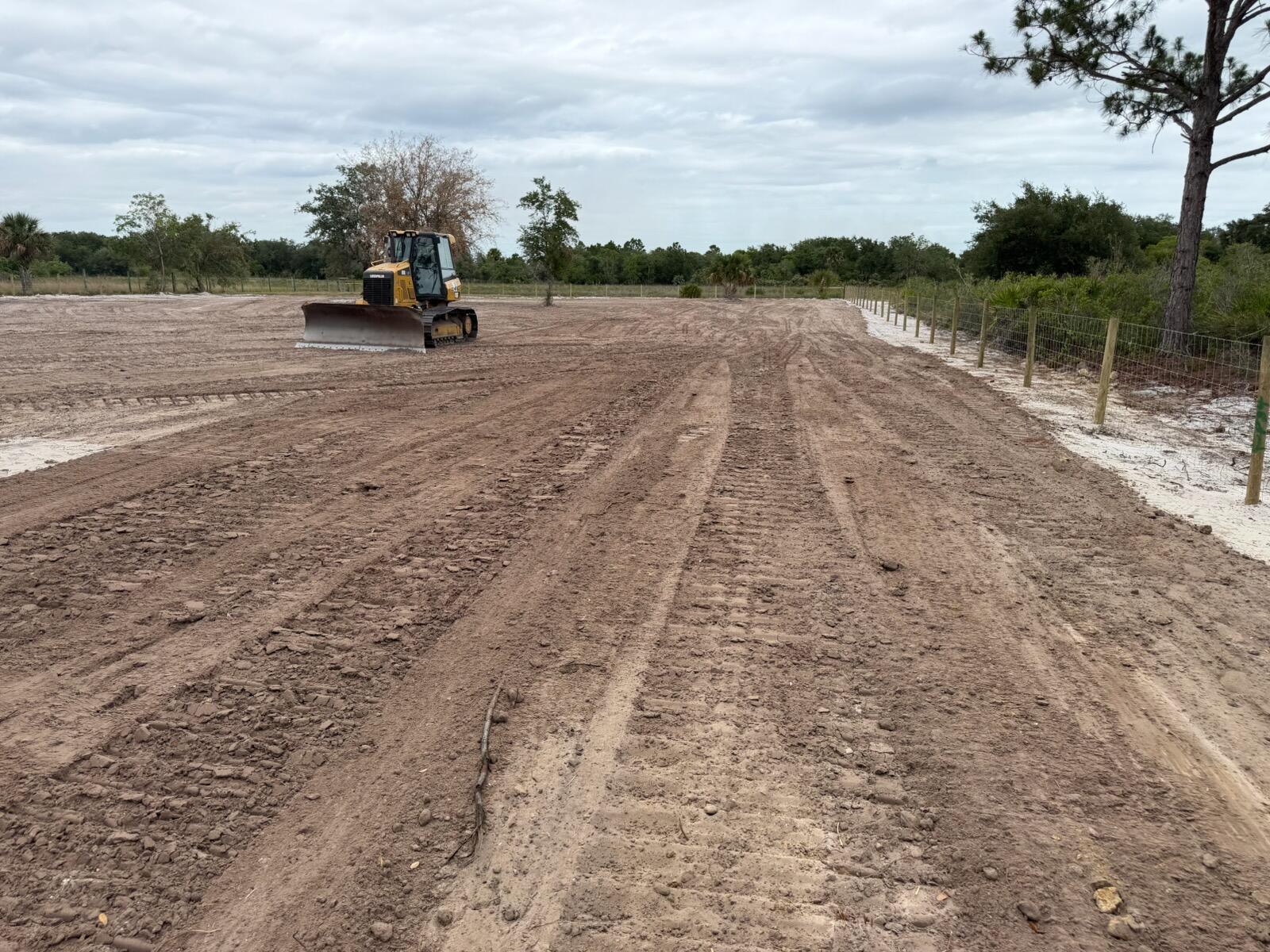 A yellow bulldozer sits on a large, cleared dirt lot next to a wire fence — 14667 NW 310th Street, Okeechobee FL 34972, OKEECHOBEE, FL