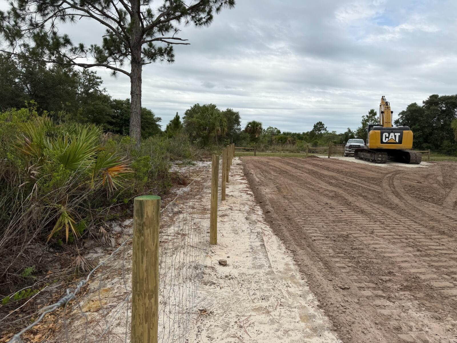 A newly installed wire fence runs along a cleared dirt lot with a parked excavator — 14667 NW 310th Street, Okeechobee FL 34972, OKEECHOBEE, FL
