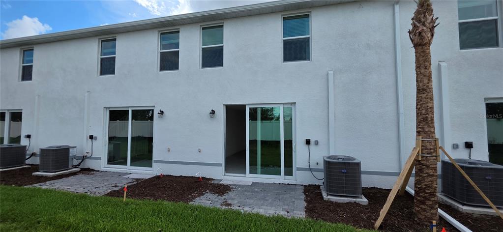 The exterior rear view of a two-story townhouse features sliding glass doors and AC units — 14432 LILAC SKY TERRACE, BRADENTON, FL