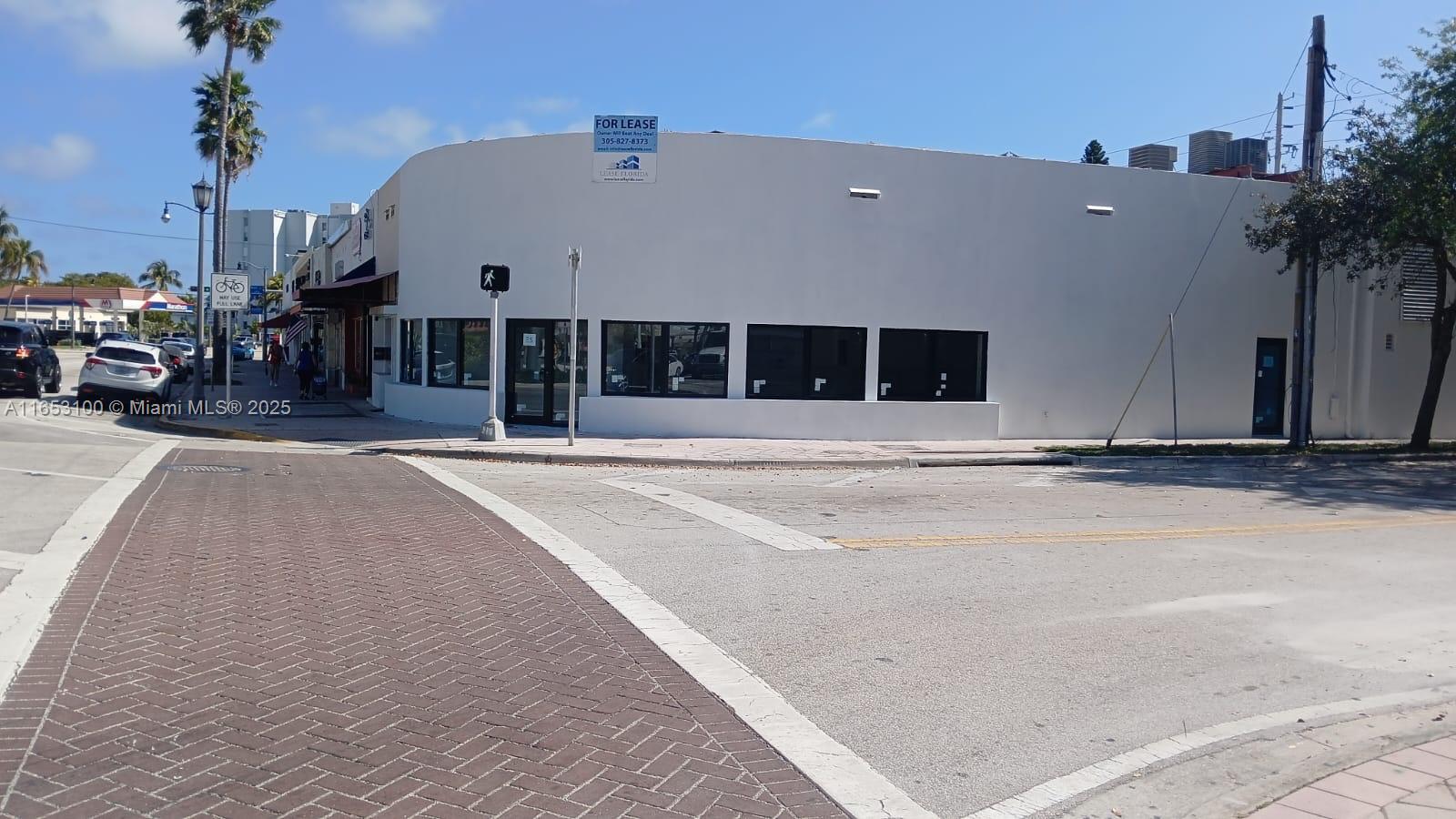 A white commercial building with large windows stands on a corner lot under a blue sky — 940 71st St, Miami Beach FL 33141, MIAMI BEACH, FL