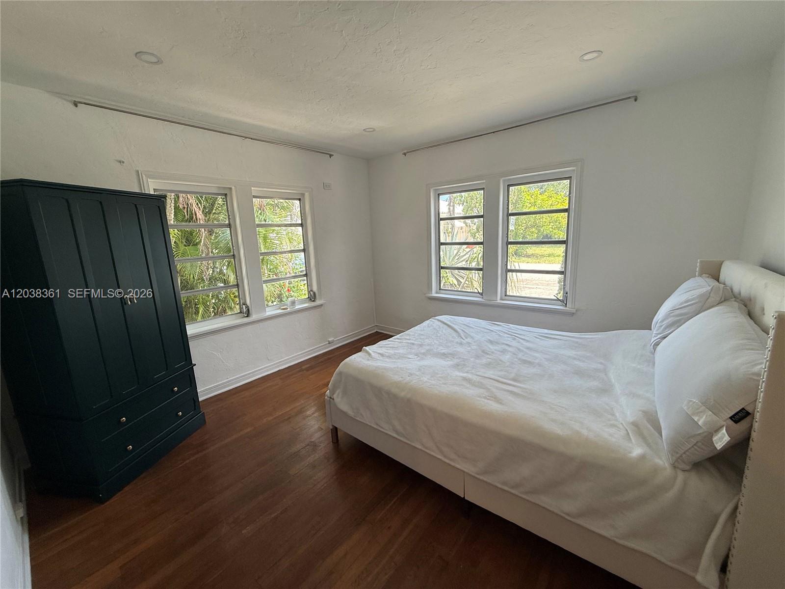 A living room features wood-look flooring, a stone fireplace with a wooden mantel, and windows — 1719 Hayes St, Hollywood FL 33020, HOLLYWOOD, FL