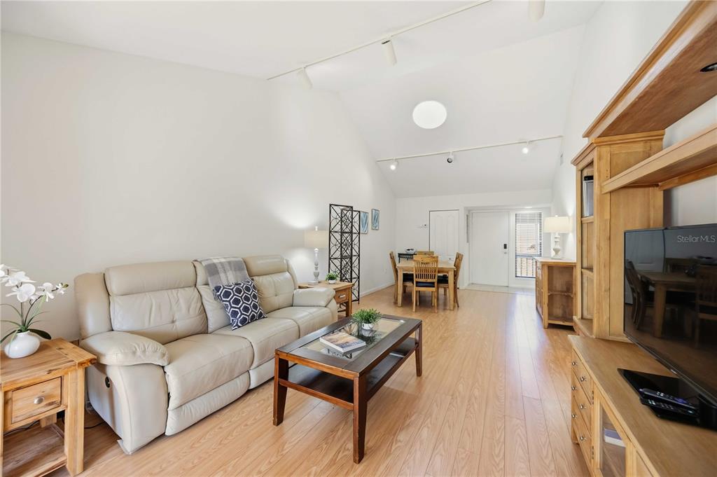 A living room with light wood flooring, a beige sofa, and a vaulted ceiling — 1626 BROOKHOUSE DRIVE UNIT 235, SARASOTA, FL