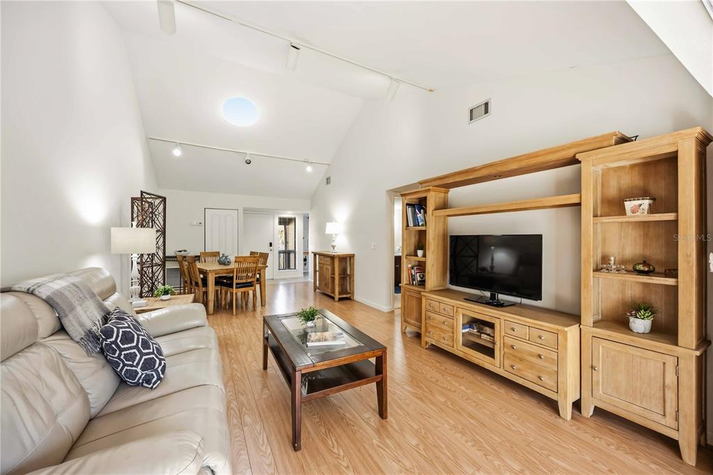 A living room with vaulted ceilings, light wood flooring, and a large wooden entertainment center — 1626 BROOKHOUSE DRIVE UNIT 235, SARASOTA, FL