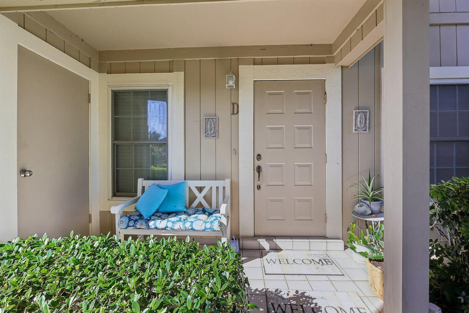 A covered front porch features a white bench, a welcome mat, and a tan door — 9240 SE Riverfront # D, Jupiter FL 33469, JUPITER, FL